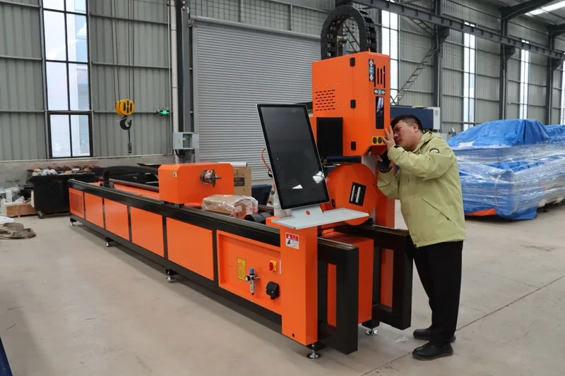 A worker at an industrial cutting machine in a manufacturing hall.